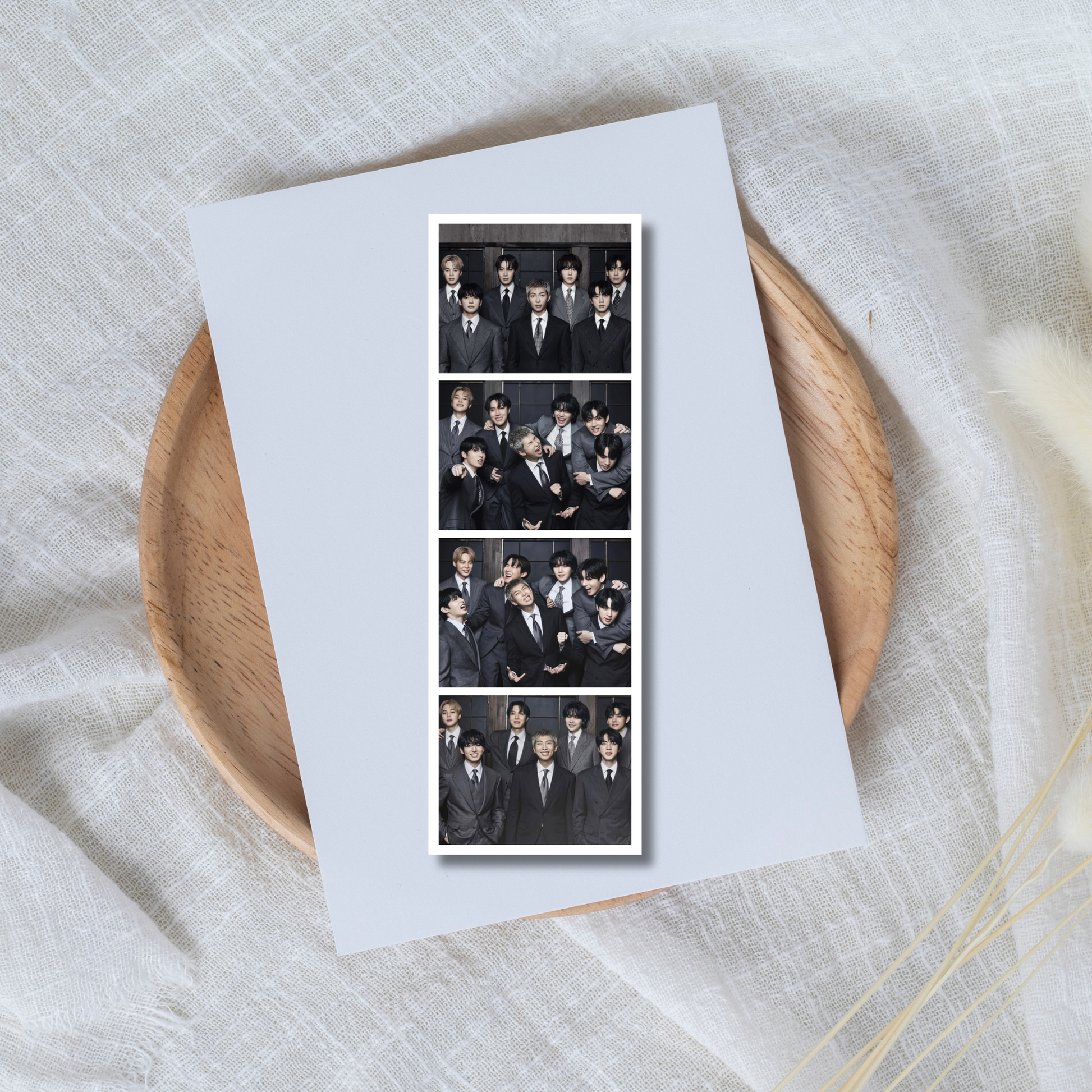Collage of a BTS members on a white card with a wooden plate and fabric background